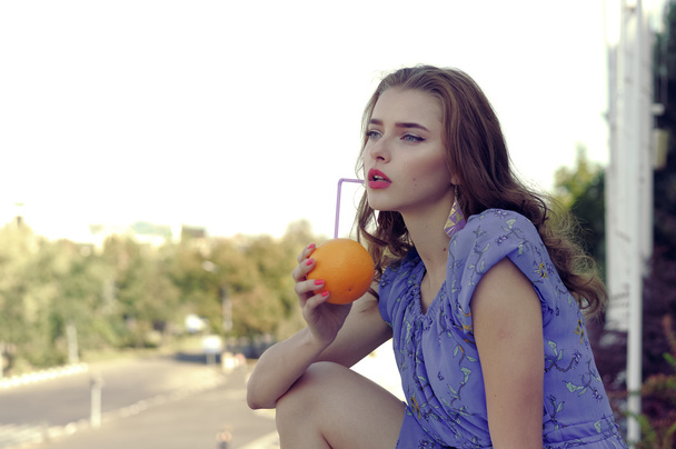 Girl holds an orange in her hands - Фото, изображение