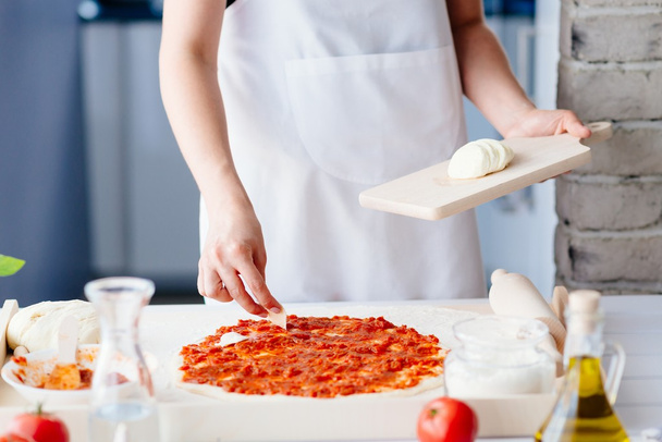 女性はピザのモッツァレラチーズのスライスを置く - 写真・画像