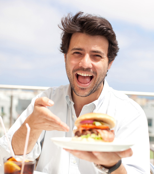 Jeune homme mangeant un hamburguer
 - Photo, image