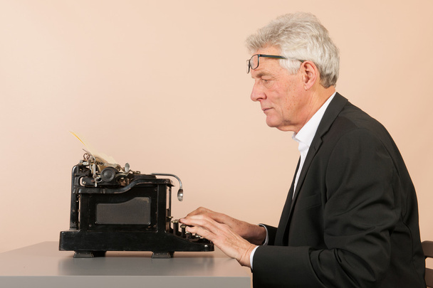 Ανώτερος άνθρωπος με παλαιά γραφομηχανή - Φωτογραφία, εικόνα
