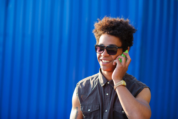 happy young black african man with cell phone having conversation on mobile - 写真・画像