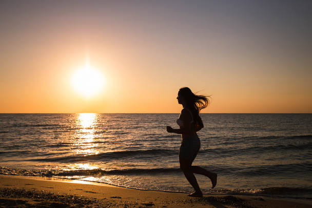 Woman running on the beach at sunset - Photo, Image
