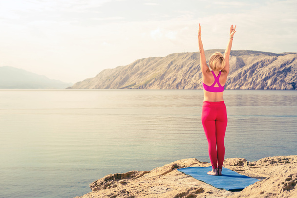 Woman meditating in yoga tree pose at the sea and mountains - Φωτογραφία, εικόνα