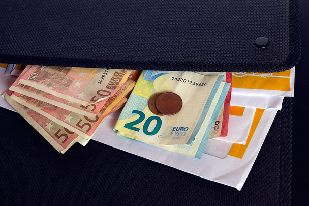 Les billets et enveloppes en euros se trouvent sur un dossier noir pour les documents
. - Photo, image