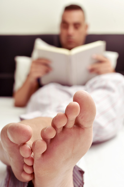 mladý muž s knihou v posteli - Fotografie, Obrázek