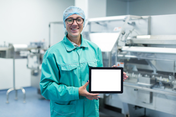 farmaceutische fabriek werknemer met een tablet in zijn handen toont apparatuur - Foto, afbeelding
