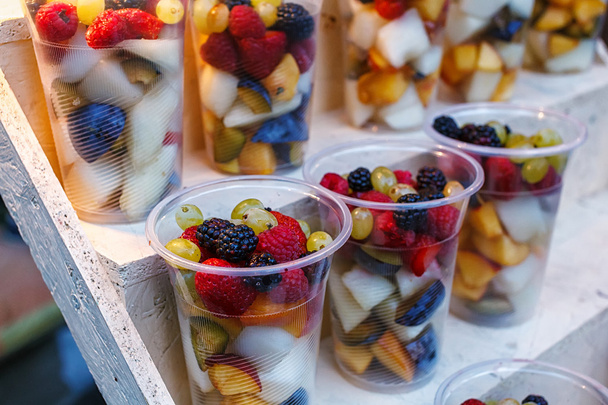Copos de plástico de frutas fatiadas. Morango, amora, kiwi, abacaxi, framboesa, ameixa, uvas, melão à venda para ir
 - Foto, Imagem