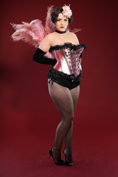 Sexy burlesco pin up mulher com cabelo loiro longo vestido de rosa e preto. Estúdio moda tiro isolado no fundo vermelho
. - Foto, Imagem