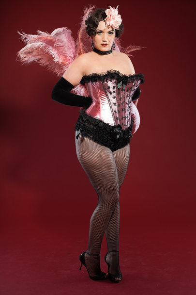 sexy burleske pin-up vrouw met lang blond haar gekleed in roze en zwart. Studio mode schot geïsoleerd op rode achtergrond. - Foto, afbeelding