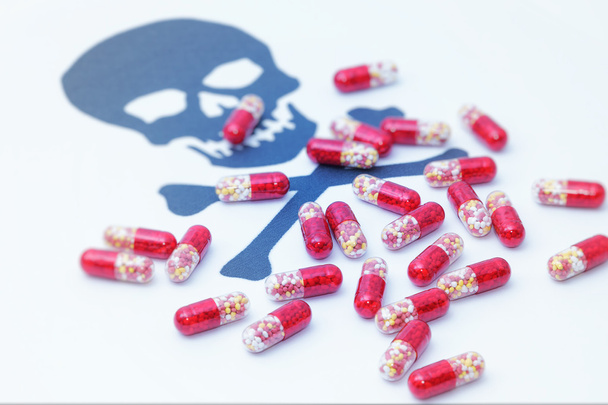Медицинские таблетки, льющиеся на знак опасности черепа
 - Фото, изображение