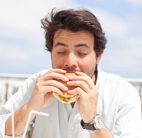 Jeune homme mangeant un hamburguer
 - Photo, image