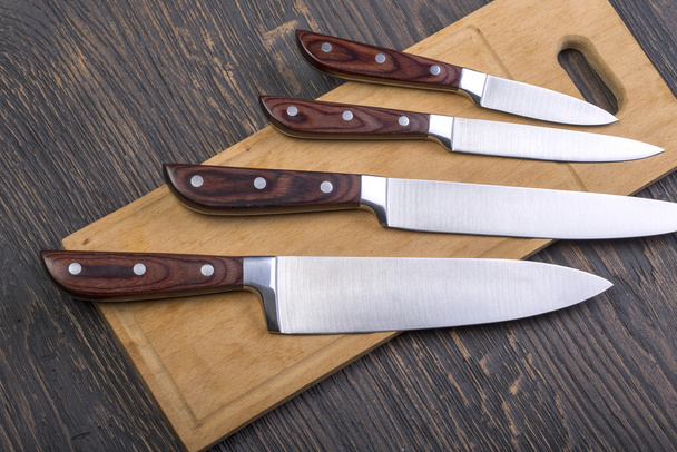  Couteaux de cuisine sur une planche à découper
 - Photo, image