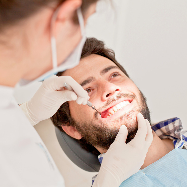 młody człowiek szczęśliwy i kobieta w badanie stomatologiczne u dentysty - Zdjęcie, obraz