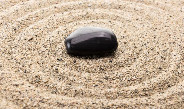 Μαύρο βασάλτη πέτρα στην άμμο που μιμείται το νερό κυματισμοί - Φωτογραφία, εικόνα