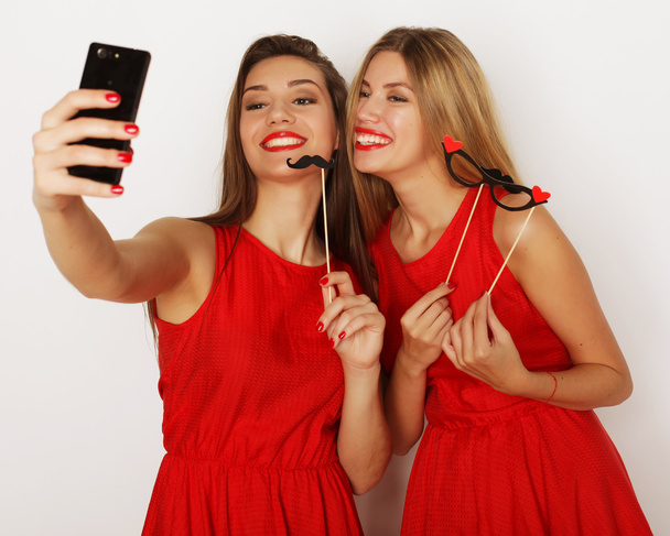 two women wearing red dress taking selfie - Foto, imagen