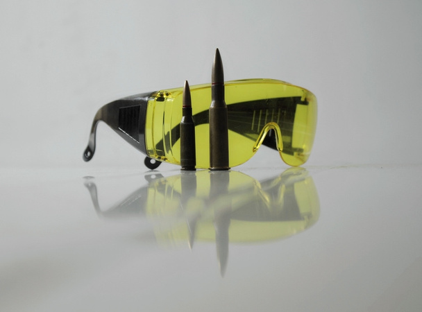 Shooters equipment. Special yellow shooting glasses and rifle bullets isolated - Photo, Image