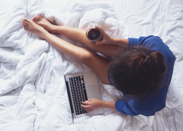 Giovane donna che beve caffè a casa nel suo letto e la controlla
  - Foto, immagini
