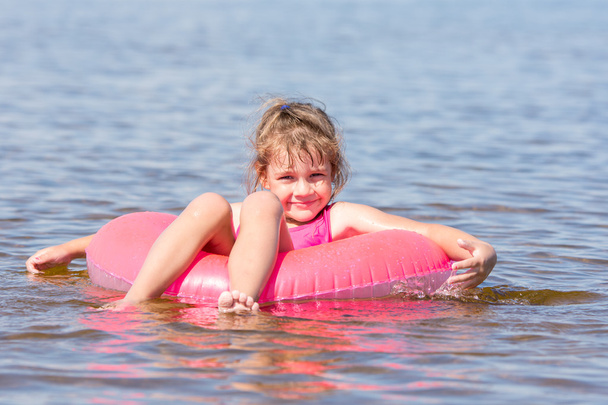5 歳の女の子水泳の膝の上に座って川を泳ぐし、楽しくフレームに見える - 写真・画像
