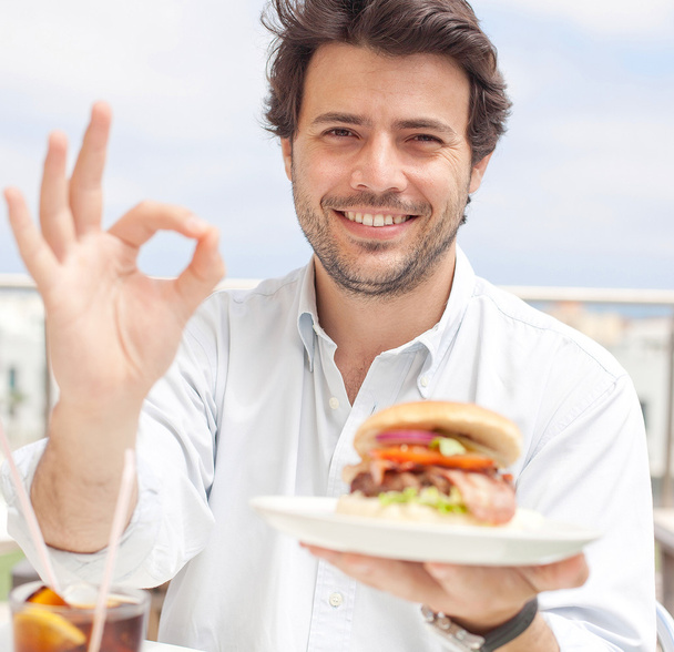 若い男性が、hamburguer を食べて - 写真・画像