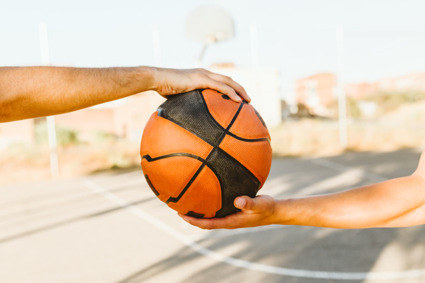 Portrait of two basketball players holding a basket ball on court. - 写真・画像