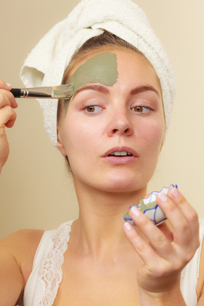 Woman applying with brush clay mud mask to her face  - Foto, Imagen