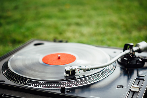 vinyl disc playing on turntable, green grass background - Photo, Image