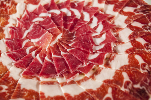Circular decorative arrangement of iberian cured ham on plate - Photo, Image