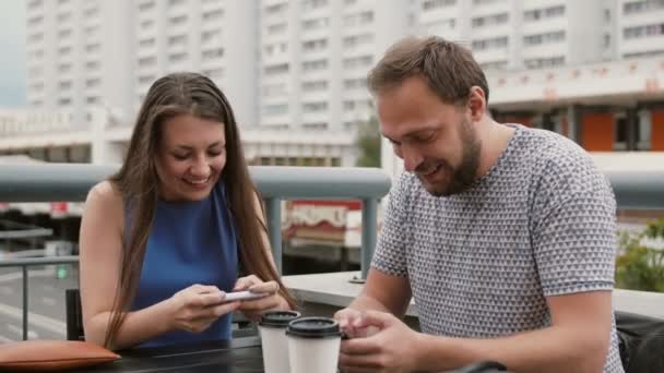 beautiful young couple playing the game online on their smartphones. She wins, the guy loses 4K - Materiał filmowy, wideo