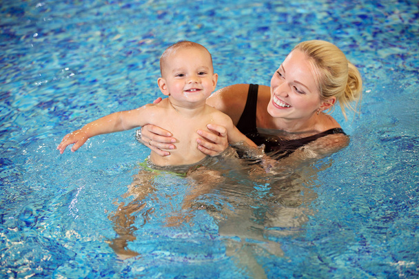 Young mother and little son having fun in a swimming pool - Photo, Image