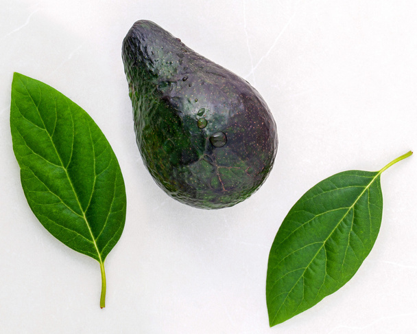 Gezond voedsel concept. Close-up verse avocado en bladeren op marbl - Foto, afbeelding