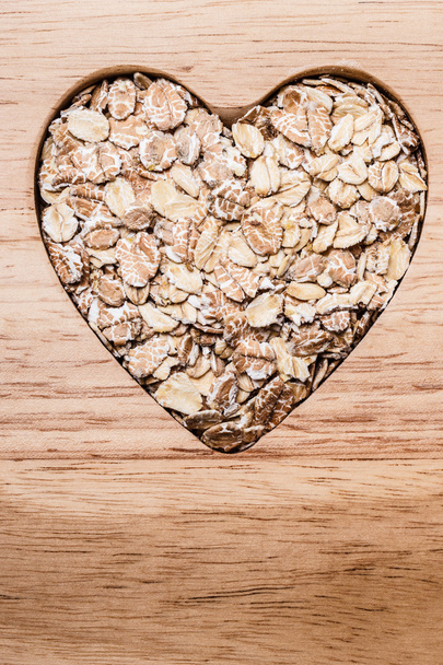 Oat cereal heart shaped on wooden surface. - 写真・画像