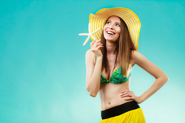 Mujer en sombrero amarillo sosteniendo concha blanca
 - Foto, Imagen
