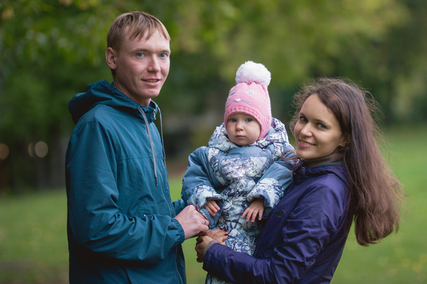 Famille heureuse : Père, Mère et enfant - petite fille dans le parc d'automne : papa, maman bébé posant en plein air, gros plan
 - Photo, image