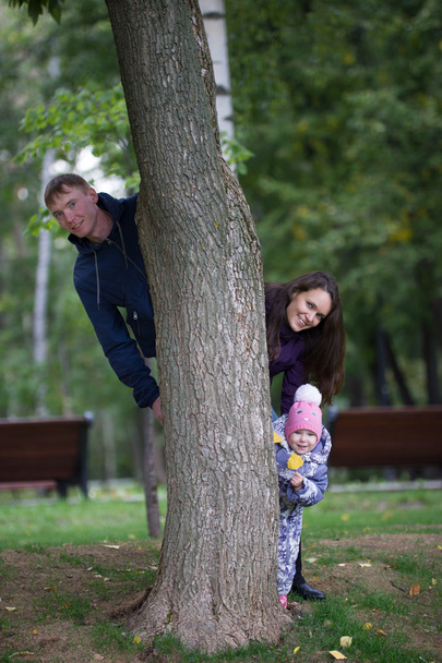 Gelukkige familie: vader, moeder en kind-klein meisje wandelen in de herfst Park: Mammy het vliegtuig spelen - Foto, afbeelding