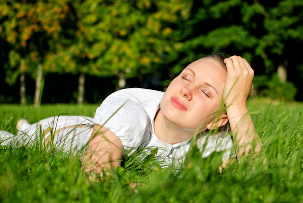Nuori nainen rentouttava nurmikolla puistossa
 - Valokuva, kuva