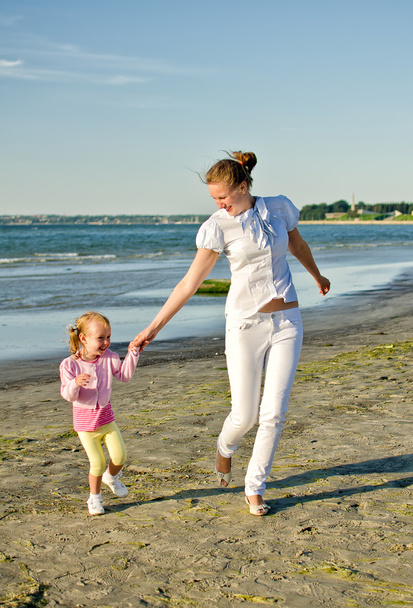 Mother and daughter having fun near the sea - Фото, зображення