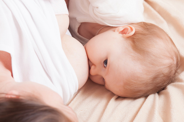 赤ちゃんがベッドで横になっている母乳ミルク ママを食べる - 写真・画像