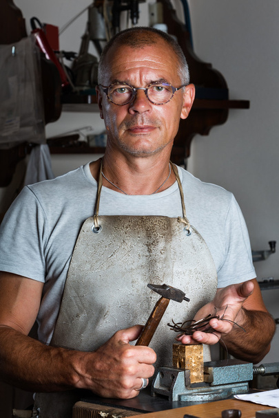 Goldsmith sosteniendo piezas de Martillo y Plata Delgada
 - Foto, imagen