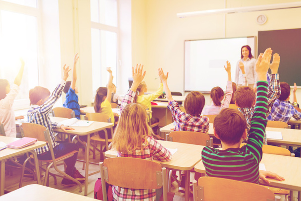 group of school kids raising hands in classroom - Fotografie, Obrázek