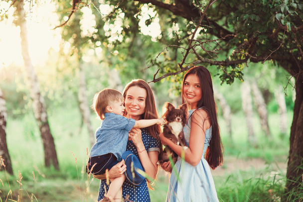 Beautiful happy family resting in nature. Two women - mom and aunt play with a boy in the Park. soft focus - Fotó, kép