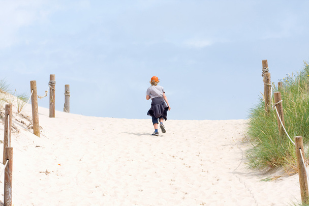 The lonely boy walking through a sand dune - Photo, Image