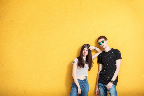 Young couple looking cool on yellow wall - 写真・画像