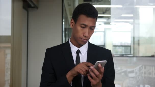 Browsing on Smartphone, Black Businessman in Office - Materiał filmowy, wideo