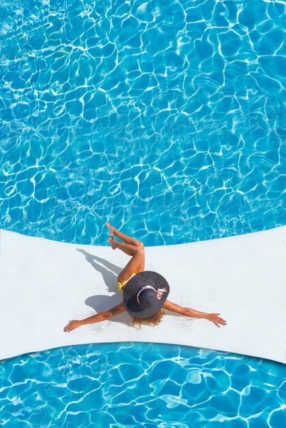 beautiful tanned sporty slim woman relaxing in swimming pool  - 写真・画像