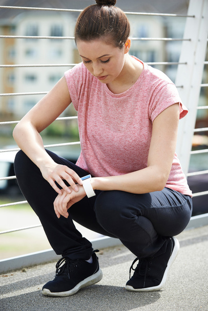Woman Looking At Activity Tracker Whilst Exercising In City - Фото, изображение