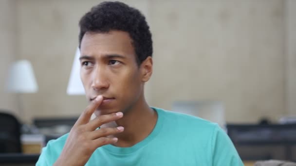 Gondolkodás töprengő fekete fiatal ember az irodában, portré - Felvétel, videó