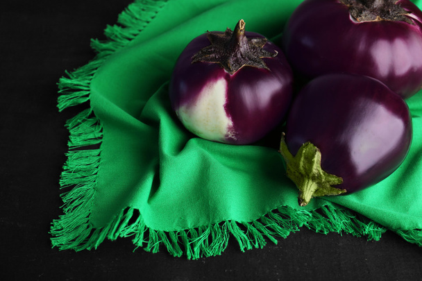 Round eggplants with green napkin on black background - Fotografie, Obrázek