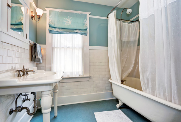 Інтер'єр синьої ванної кімнати з білою плиткою оздоблення стін, білою раковиною і ванною
 - Фото, зображення