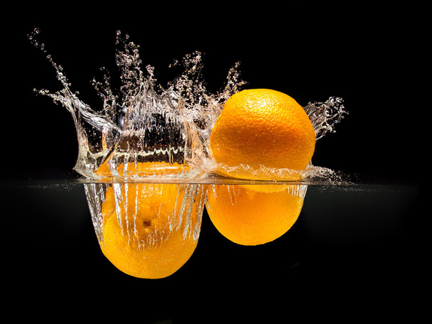 Group of fresh fruits falling in water with splash on black background - Foto, afbeelding