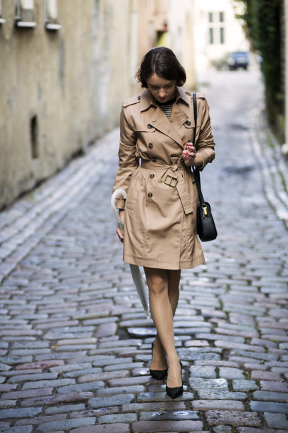 Woman at beige coat with handbag looking shoe - Фото, зображення
